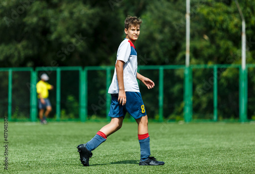 Young sport boys in white sportswear running and kicking a  ball on pitch. Soccer youth team plays football in summer. Activities for kids, training  © Natali