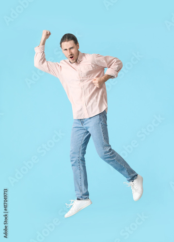 Jumping young man against c...