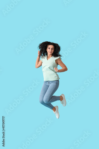 Jumping young woman against color background