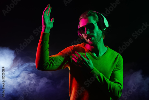 Handsome young man listening to music on dark background