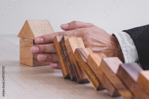 Protection finance from domino effect concept. Hands stop domino effect before destroy home.