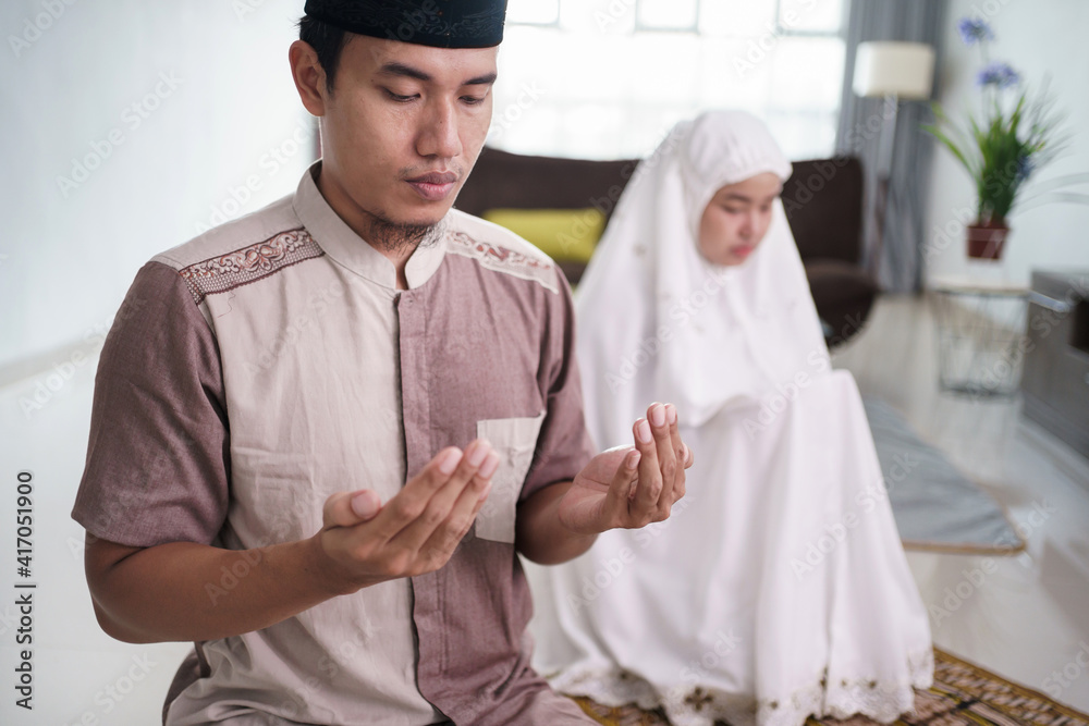 asian muslim husband and wife praying jamaah together at home