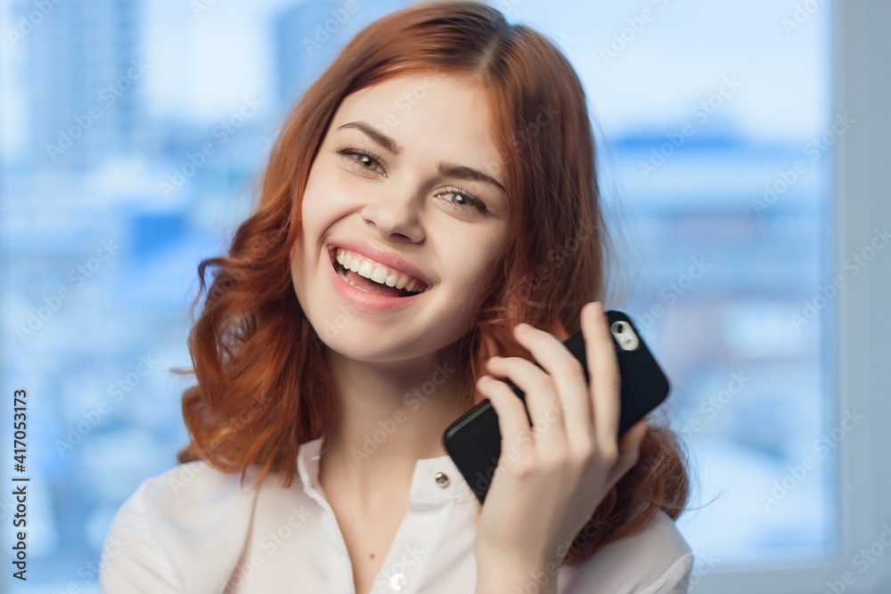 red-haired woman with a phone in her hands communicating an official red-haired woman with a phone in her hands communicating an official