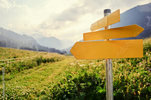 Obraz na plátně Yellow empty signboard with pointer against beautiful mountains landscape, Tirol Alps, Austria