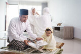 portrait of happy muslim family with children reading quran and pray together at home