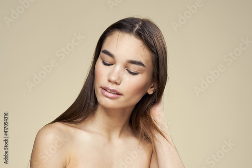 Pretty woman naked shoulders long hair body care beige background