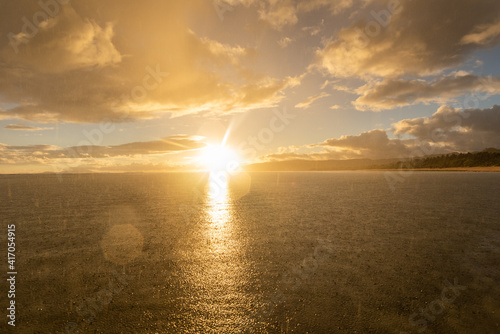 Soft rain falling on the sea with a gorgeous sunrise on horizon creating a beautiful lens flare. Iriomote Island  natural world heritage.