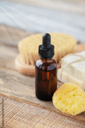 Natural organic herbal essential oil in apothecary bottles. Gentle skin care, aromatherapy, atmosphere of relaxation, anti-stress. Sponge, brush, handmade soap, wooden background. Copy space for text
