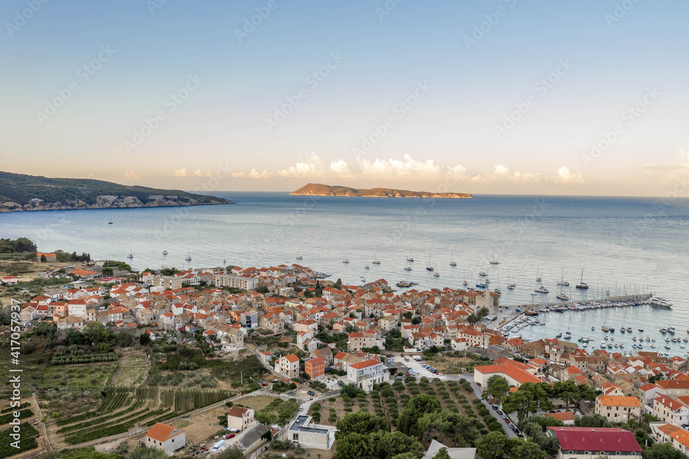 Aerial drone shot of adriatic sea Komiza town on Vis Island with view of Bisevo Island in Croatia summer sunrise