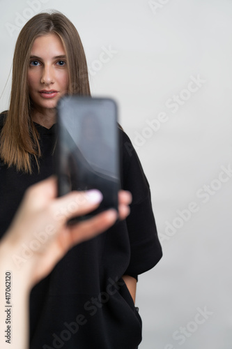 portrait of a girl who is being photographed on a mobile phone. White background.