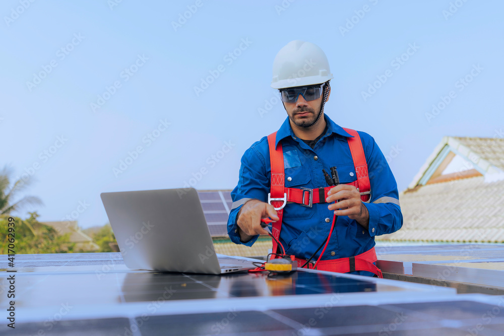 An Engineer use a laptop computer to inspection the solar panels at roof top An Engineer use a laptop computer to inspection the solar panels at roof top