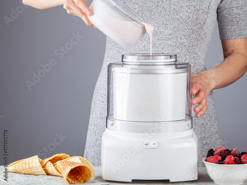 Obraz na płótnie A caucasian woman is pouring homemade all natural ice cream mixture into an ice cream maker machine