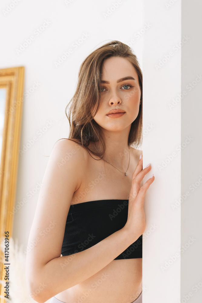 Beautiful young woman beauty fashion model with long hair in blsck top looking at camera on the white background Beautiful young woman beauty fashion model with long hair in blsck top looking at camera on the white background