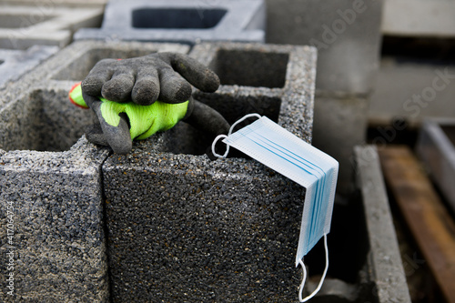 Coronavirus COVID-19 protective mask placed on concrete slag blocks with gloves