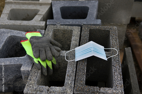 Coronavirus COVID-19 protective mask placed on concrete slag blocks with gloves
