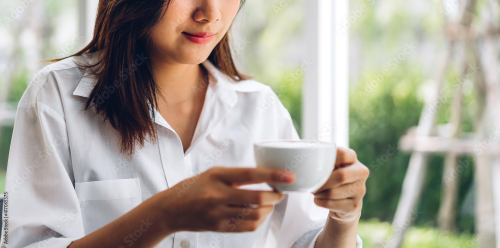 Portrait of smiling happy cheerful beautiful pretty asian woman relaxing drinking and looking at cup of hot coffee or tea.Girl felling enjoy having breakfast in holiday morning vacation on bed at home Portrait of smiling happy cheerful beautiful pretty asian woman relaxing drinking and looking at cup of hot coffee or tea.Girl felling enjoy having breakfast in holiday morning vacation on bed at home