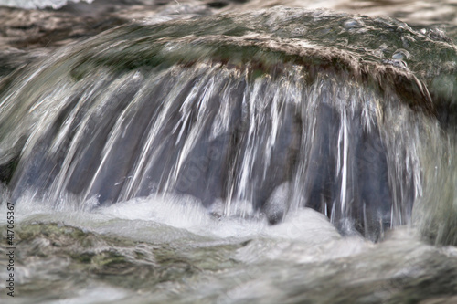 water flows over a boulder in the river