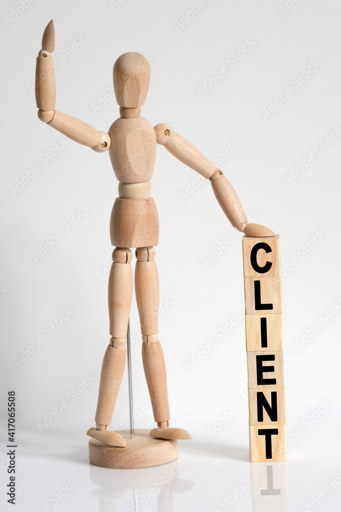 The wooden man raised his hand, and under his left hand he has cubes with the inscription - CLIENT The wooden man raised his hand, and under his left hand he has cubes with the inscription - CLIENT