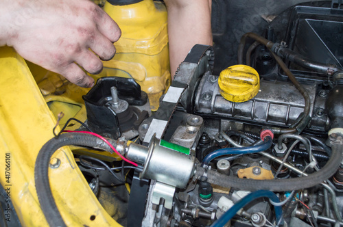 A mechanic installs a timing belt on a yellow diesel car