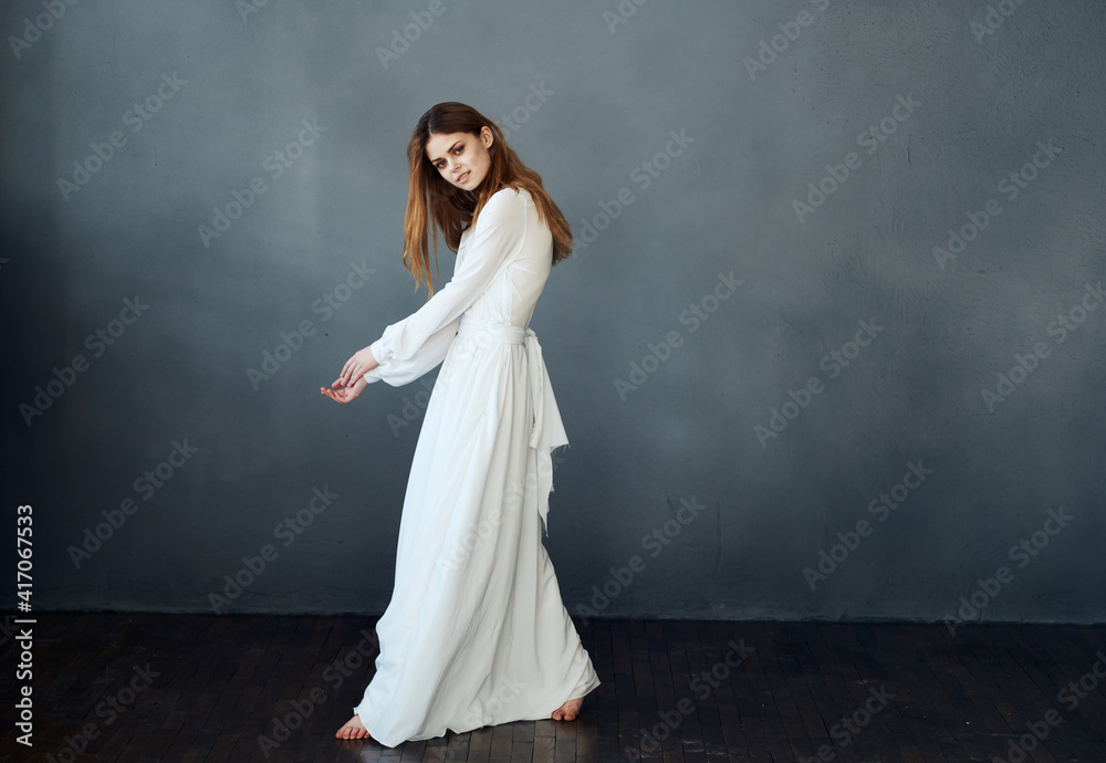 Portrait of an attractive woman in a white dress on a gray background in full growth Copy Space