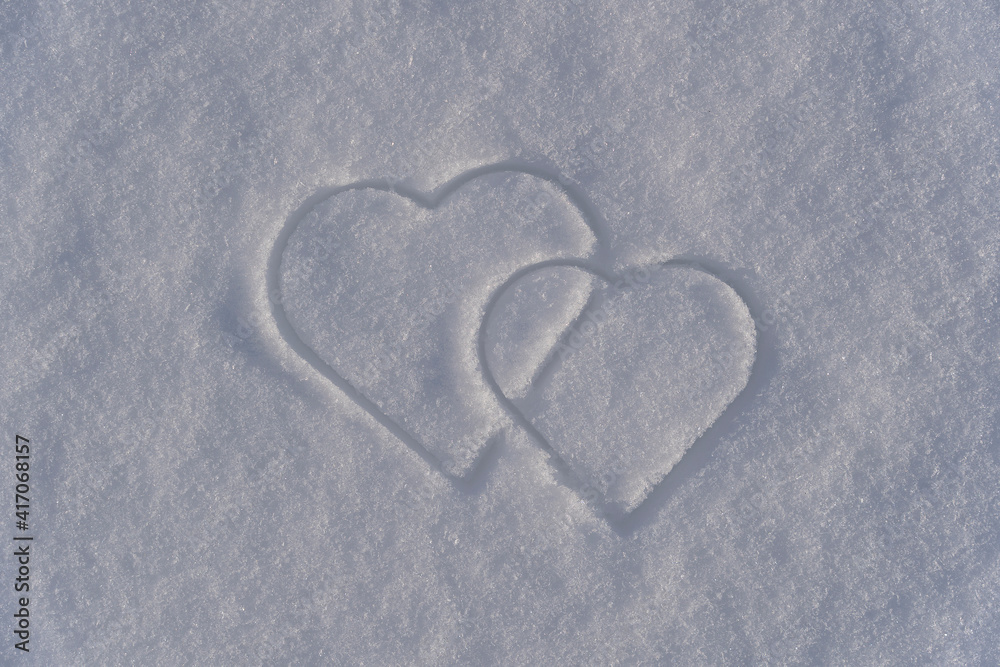 Two heart shape on a white snow in winter, close up