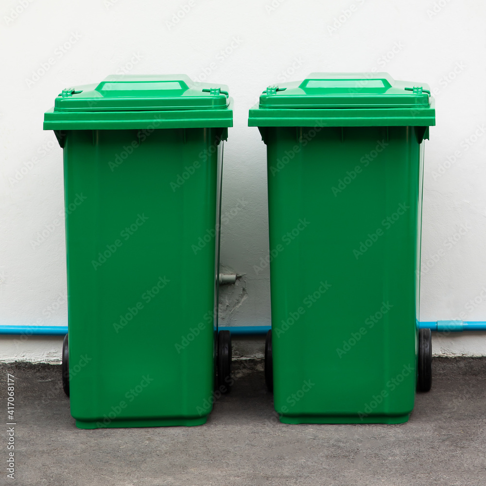 A new unbox green large bins ready to use on footpath and white concrete wall