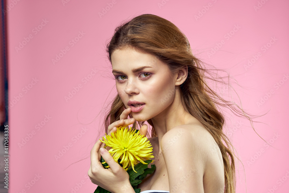 Beautiful woman naked shoulders yellow flower charm cosmetics pink background Beautiful woman naked shoulders yellow flower charm cosmetics pink background
