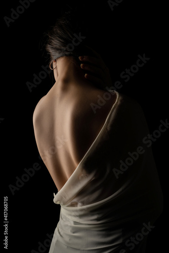 Back view of a beautiful half naked woman. Vertical shot, isolated black background.