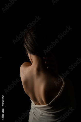 Back view of a beautiful half naked woman. Vertical shot, isolated black background.