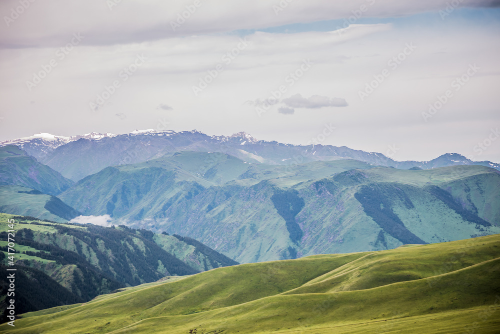 Endless steppe in the valley at the foot of the mountains, bathed in bright sunlight. Amazing view on green mountains. mountain, covered with green trees, under a blue sky with clouds. Endless steppe in the valley at the foot of the mountains, bathed in bright sunlight. Amazing view on green mountains. mountain, covered with green trees, under a blue sky with clouds.