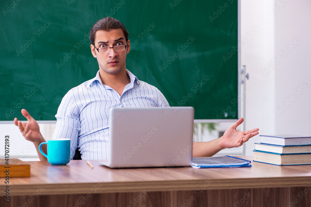 Young male teacher in front of blackboard Young male teacher in front of blackboard