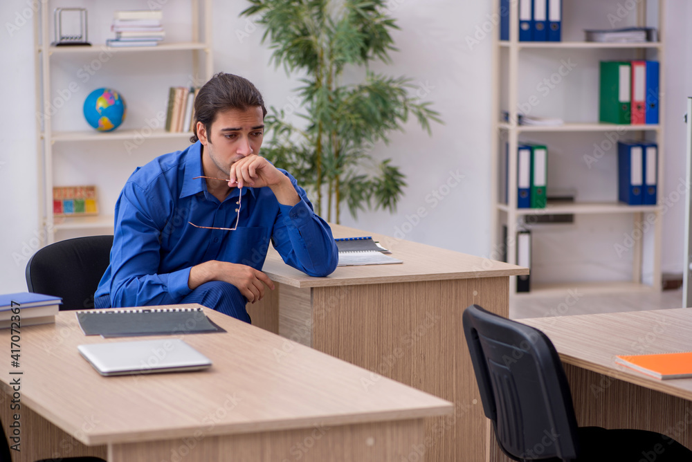 Young male teacher being tired in the classroom Young male teacher being tired in the classroom