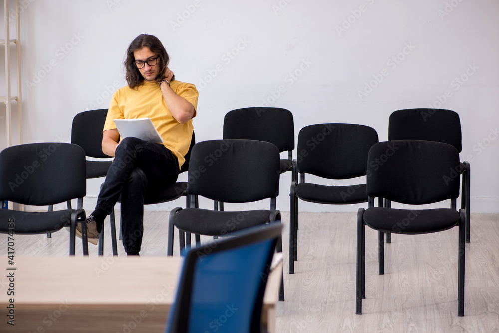 Young male student waiting for teacher in the classroom Young male student waiting for teacher in the classroom