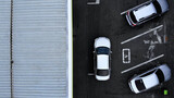 Aerial top view from drone places for disabled people on parking lot of the business center, shopping mall (supermarket) with cars and empty parking spots at day.