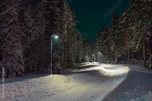 Snow-covered and plowed walkway illuminated with street light in Pitea photo