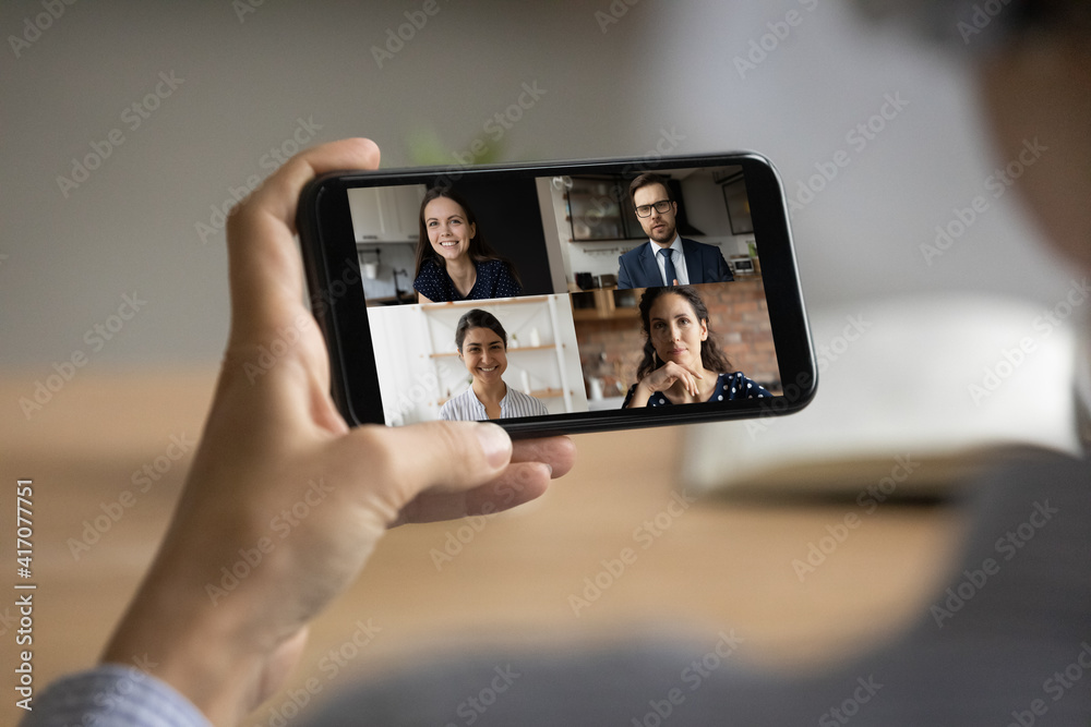 Close up of woman hold modern smartphone gadget have webcam digital online meeting with diverse businesspeople. Female employee talk speak on video call on cellphone with smiling colleagues.