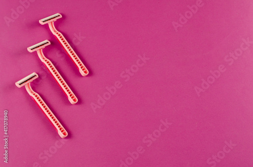 Pink plastic razors on a pink background.