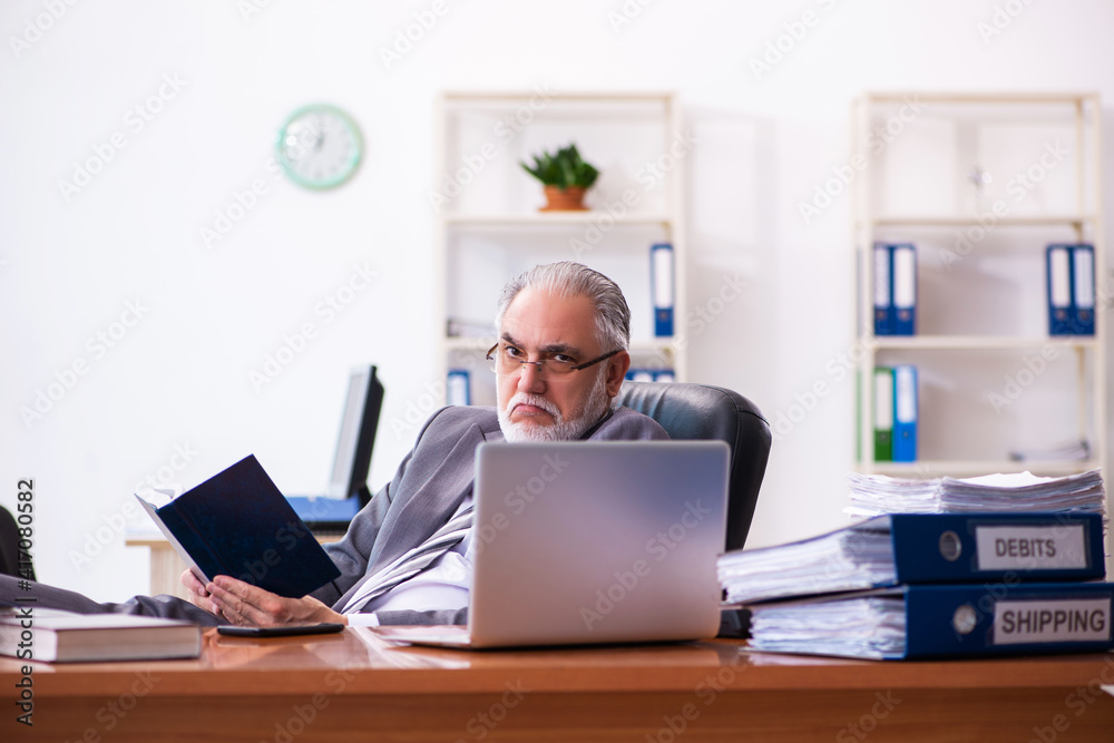 Old male businessman employee reading guidelines in the office Old male businessman employee reading guidelines in the office