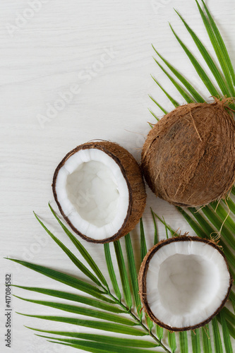 Coconuts with palm leaf on white wooden background.