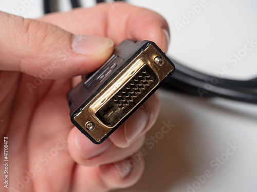 The DVI cable is black in the male hand. Cable for transmitting video images to digital display devices.