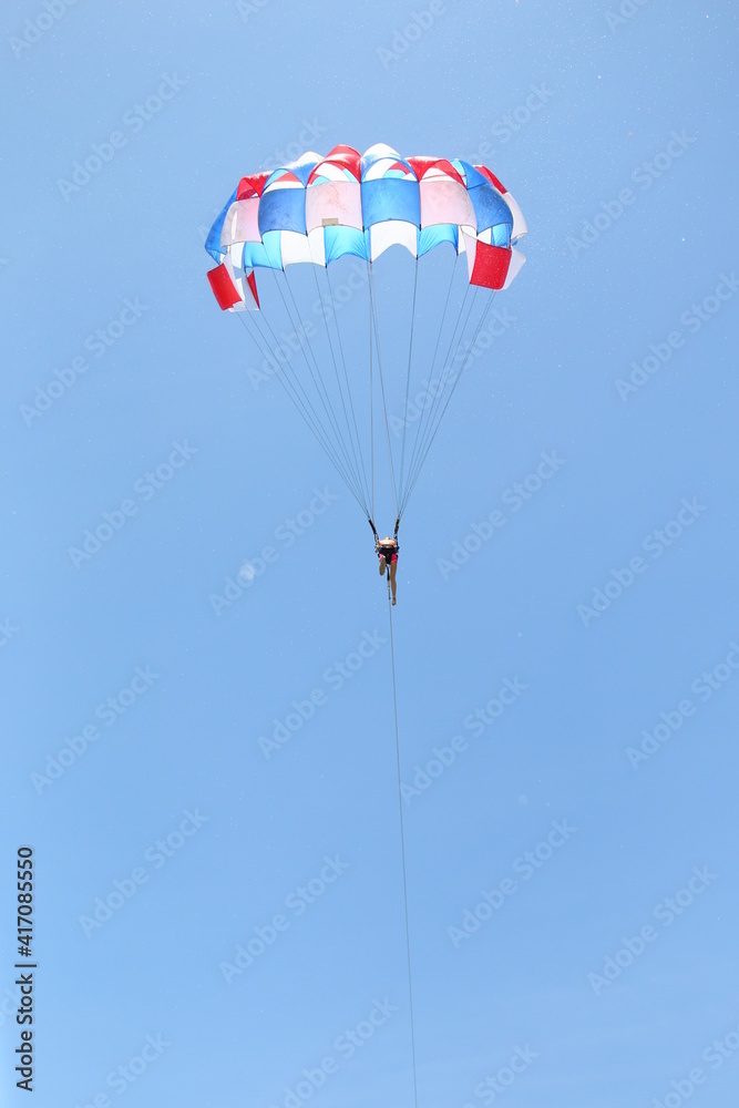 men are gliding using a parachute on the background of the blue sky. men are gliding using a parachute on the background of the blue sky.