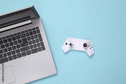 Origami paper gamepad and laptop on a blue background. Gaming concept