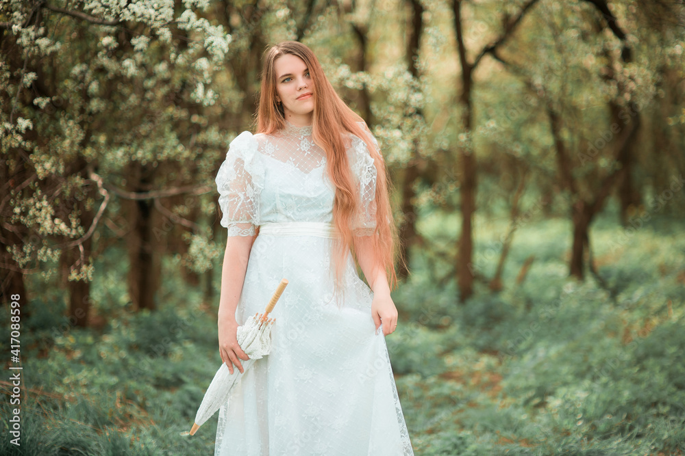 A girl in a park in a white dress and with an umbrella