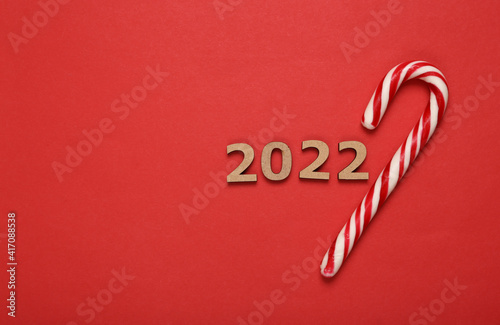 2022 and striped candy cane on red background. Christmas, new year composition