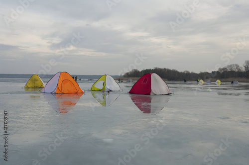 Winter fishing on the lake. Colorful tents for warm fishing in cold weather. Wallpaper. Selective focus.