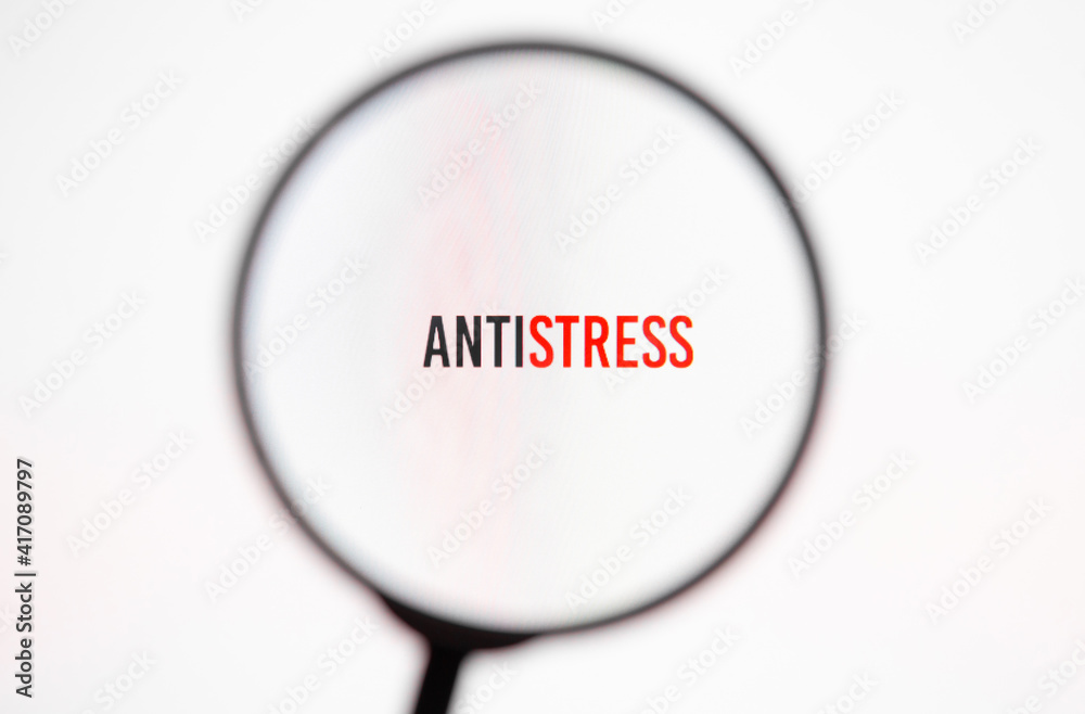Inscription antistress on white screen of the monitor through magnifying glass