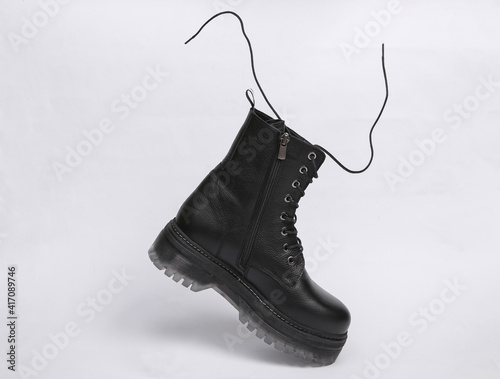 Trendy stylish leather black boot with flying laces on a white background
