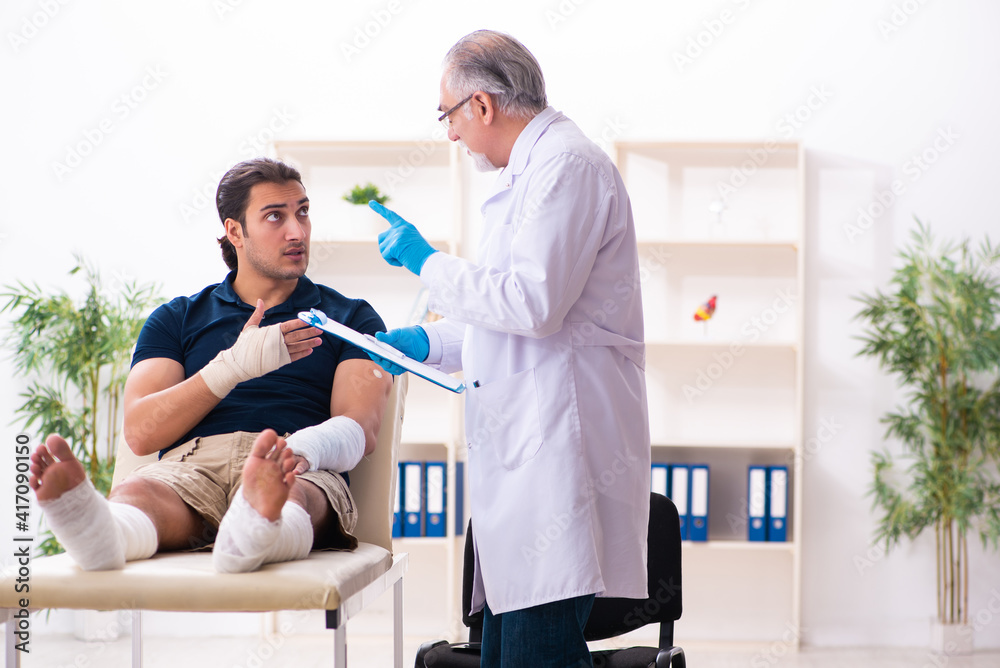 Obraz premium Young injured man visiting old doctor traumatologist