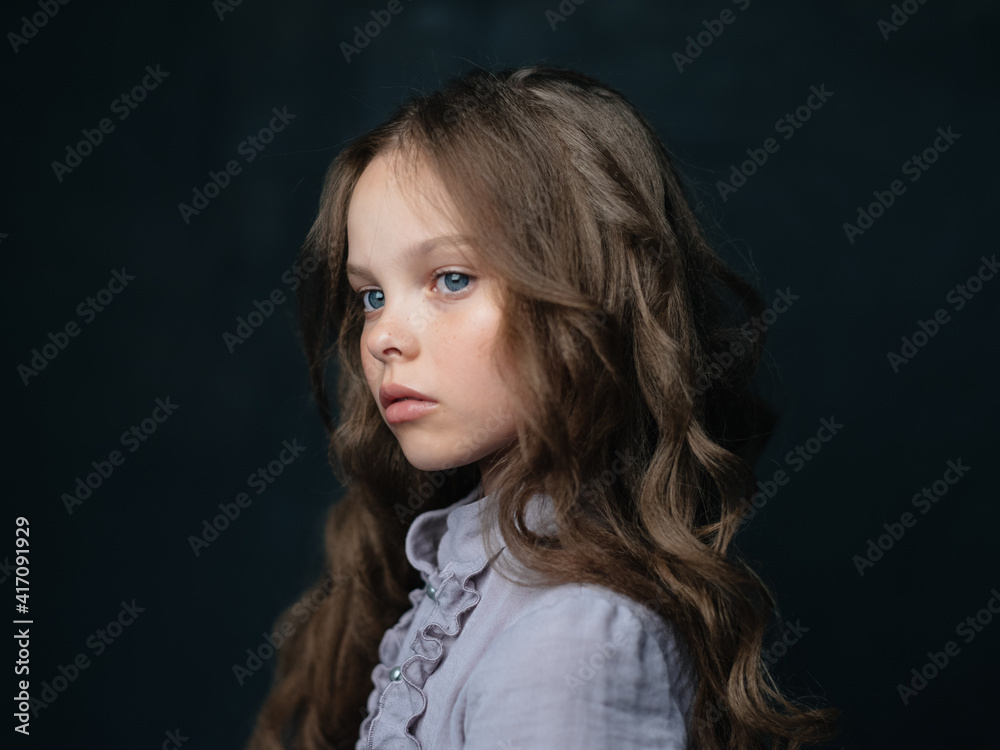 portrait of a beautiful girl in a gray dress on a dark background and curly hair blue eyes portrait of a beautiful girl in a gray dress on a dark background and curly hair blue eyes