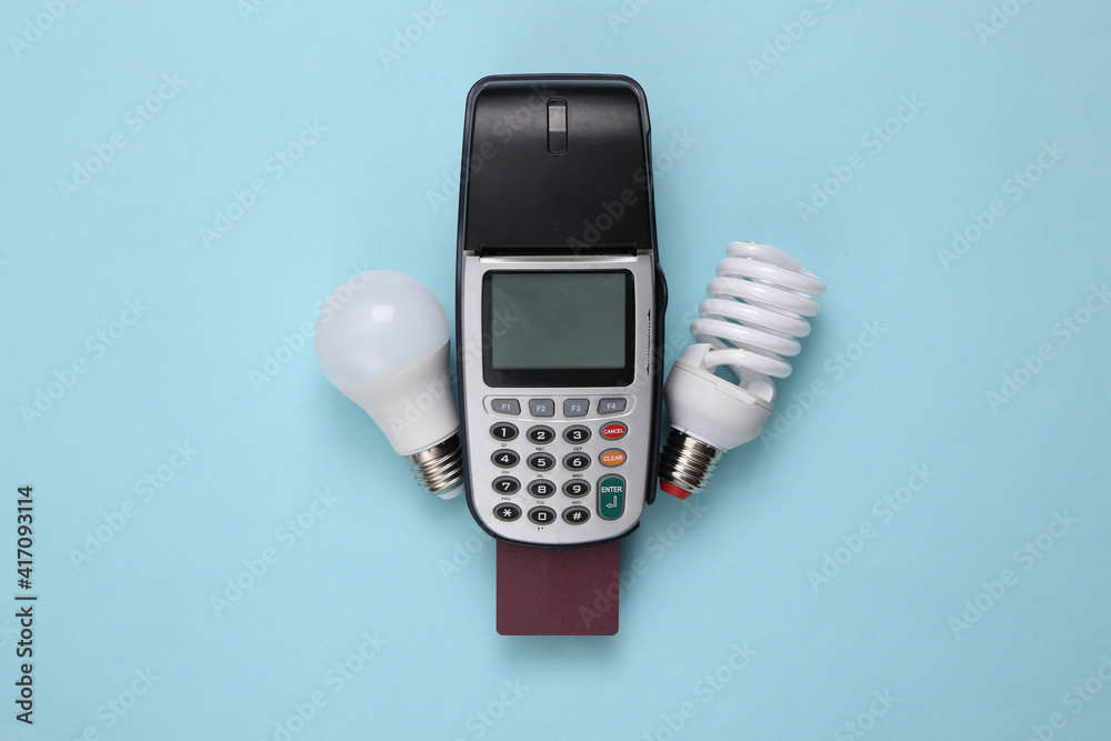 Payment terminal with bank card and light bulbs on blue background Payment terminal with bank card and light bulbs on blue background
